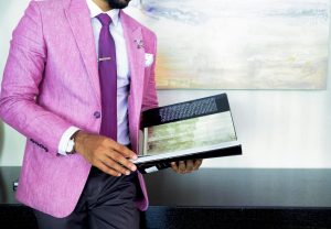 Image of man wearing bright pink jacket holding a book